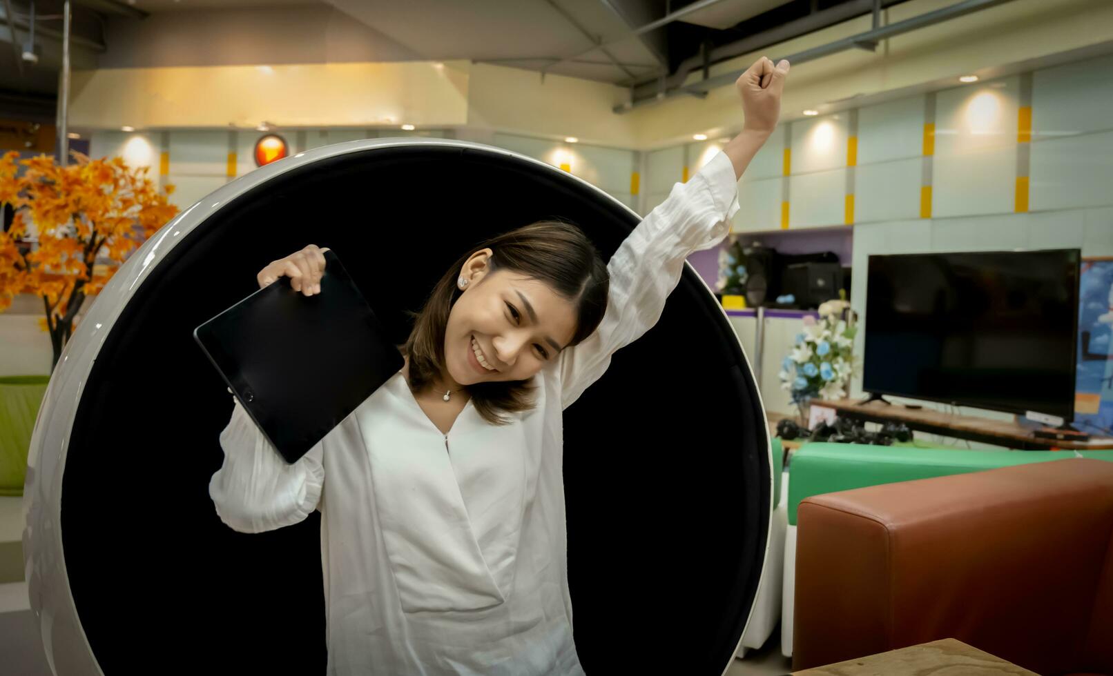 Beautiful businesswoman is glad that she was able to close the sale before the due date  while sitting on a modern round chair in the living room. photo
