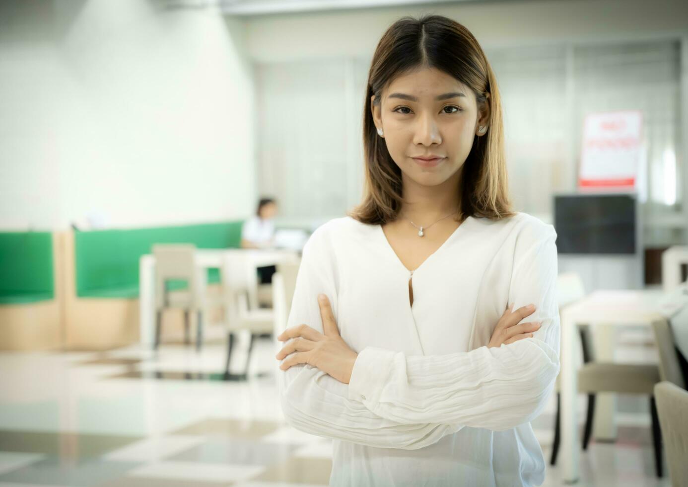 el hermosa asiático hembra profesor es en pie con brazos cruzado y mirando a el cámara con un grave cara en el aula. foto