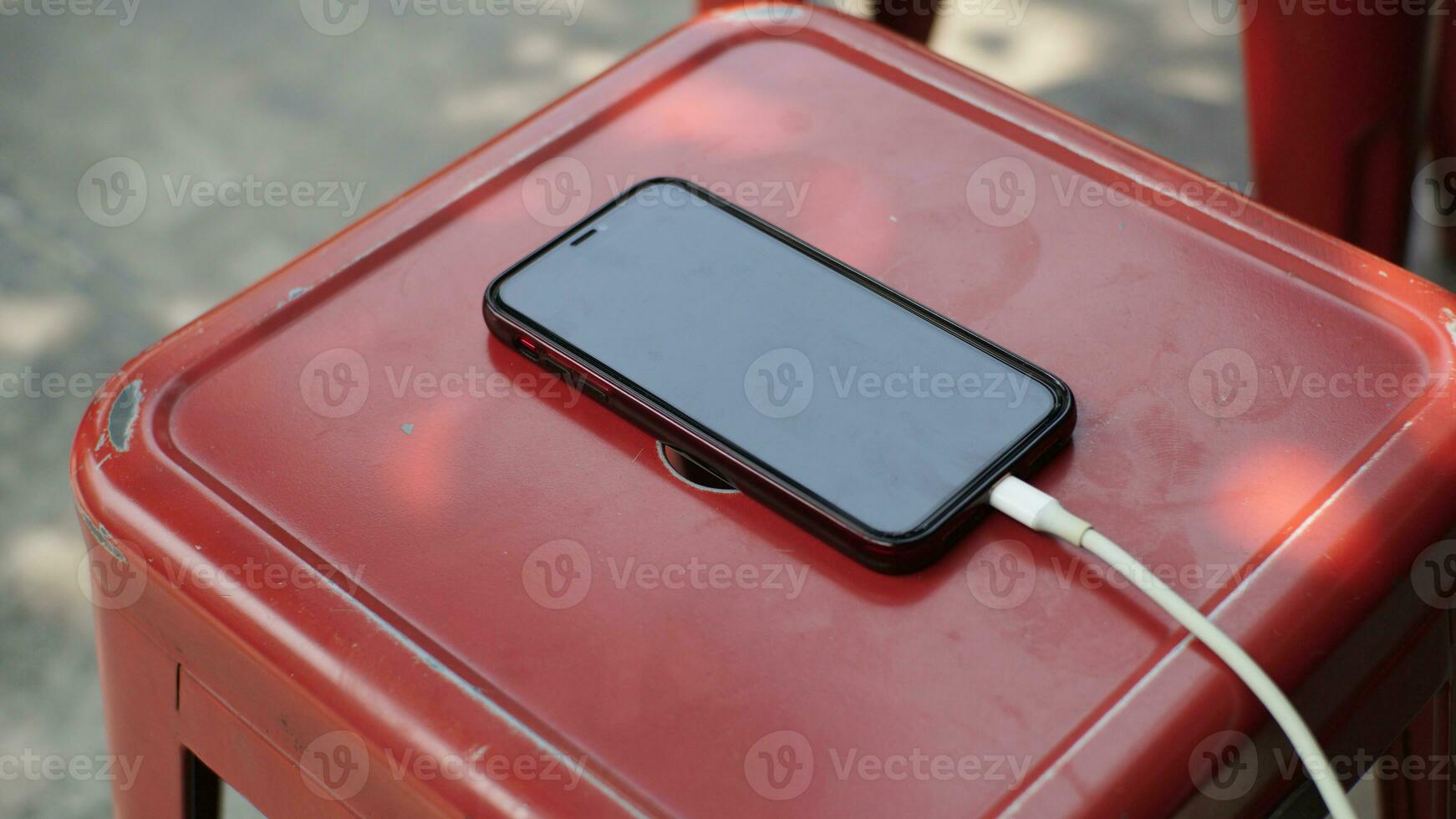 Smartphone charging on a red table in a coffee shop. photo