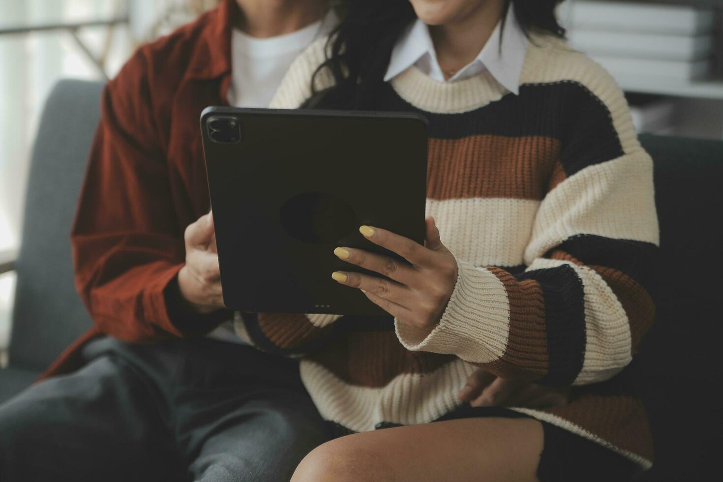 Young woman and young man using laptop while sitting by the sofa at home photo