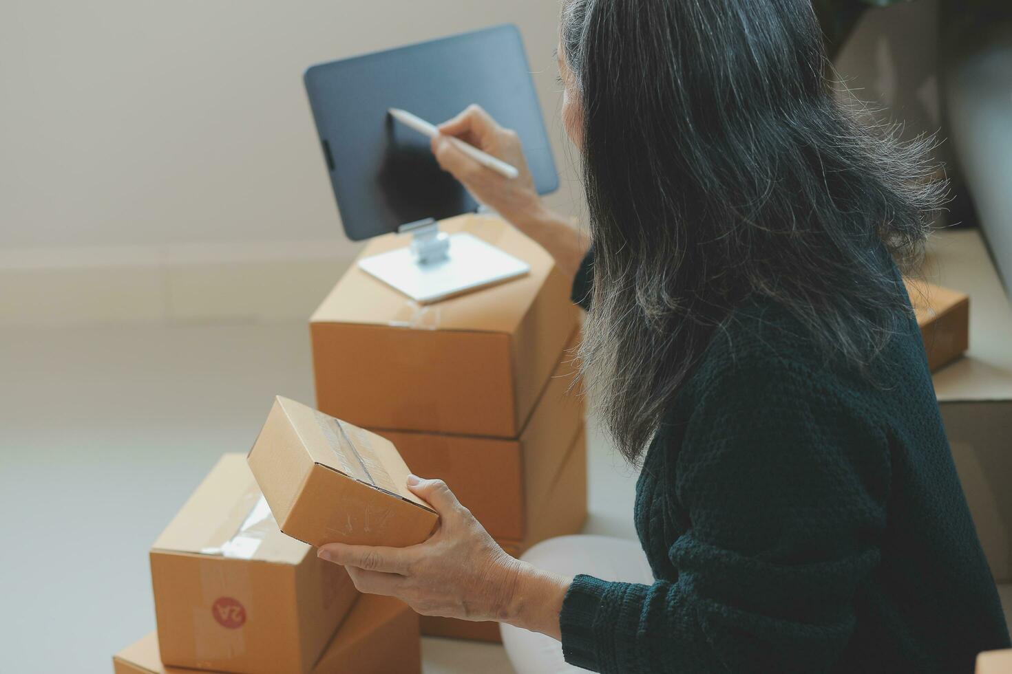 Startup SME small business entrepreneur of freelance Asian woman using a laptop with box Cheerful success Asian woman her hand lifts up online marketing packaging box and delivery SME idea concept photo