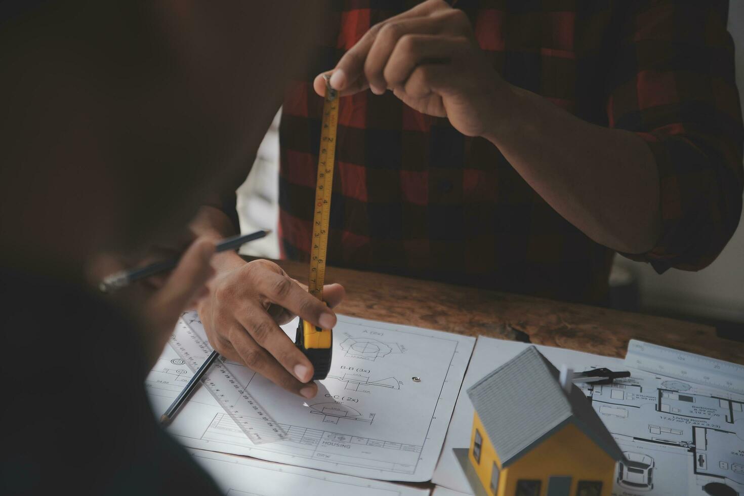 Close up of civil male engineer asian working on blueprint architectural project at construction site at desk in office. photo
