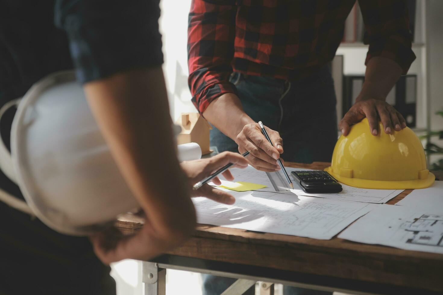 primer plano de un ingeniero civil asiático que trabaja en un proyecto arquitectónico de planos en el sitio de construcción en el escritorio de la oficina. foto