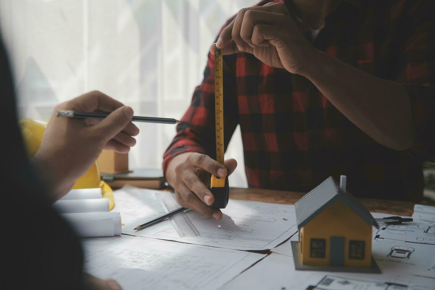 Close up of civil male engineer asian working on blueprint architectural project at construction site at desk in office. photo