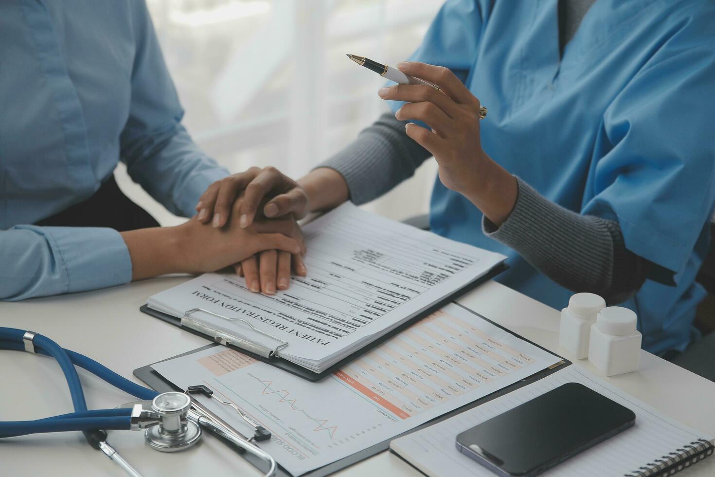 Young woman comes to clinic for heart and lungs checkup. Friendly female doctor sitting at desk in modern medical office, holding stethoscope, listening to patient's breath or heartbeat and smiling photo