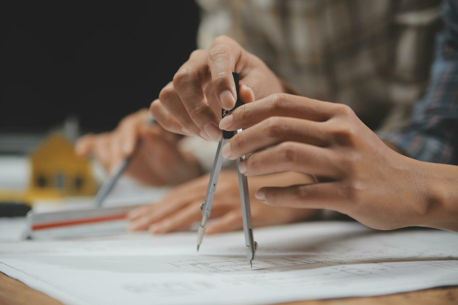 Team of multiethnic architects working on construction plans in meeting room. Engineers discussing on project in office. Mature businessman and woman standing around table working on blueprint. photo