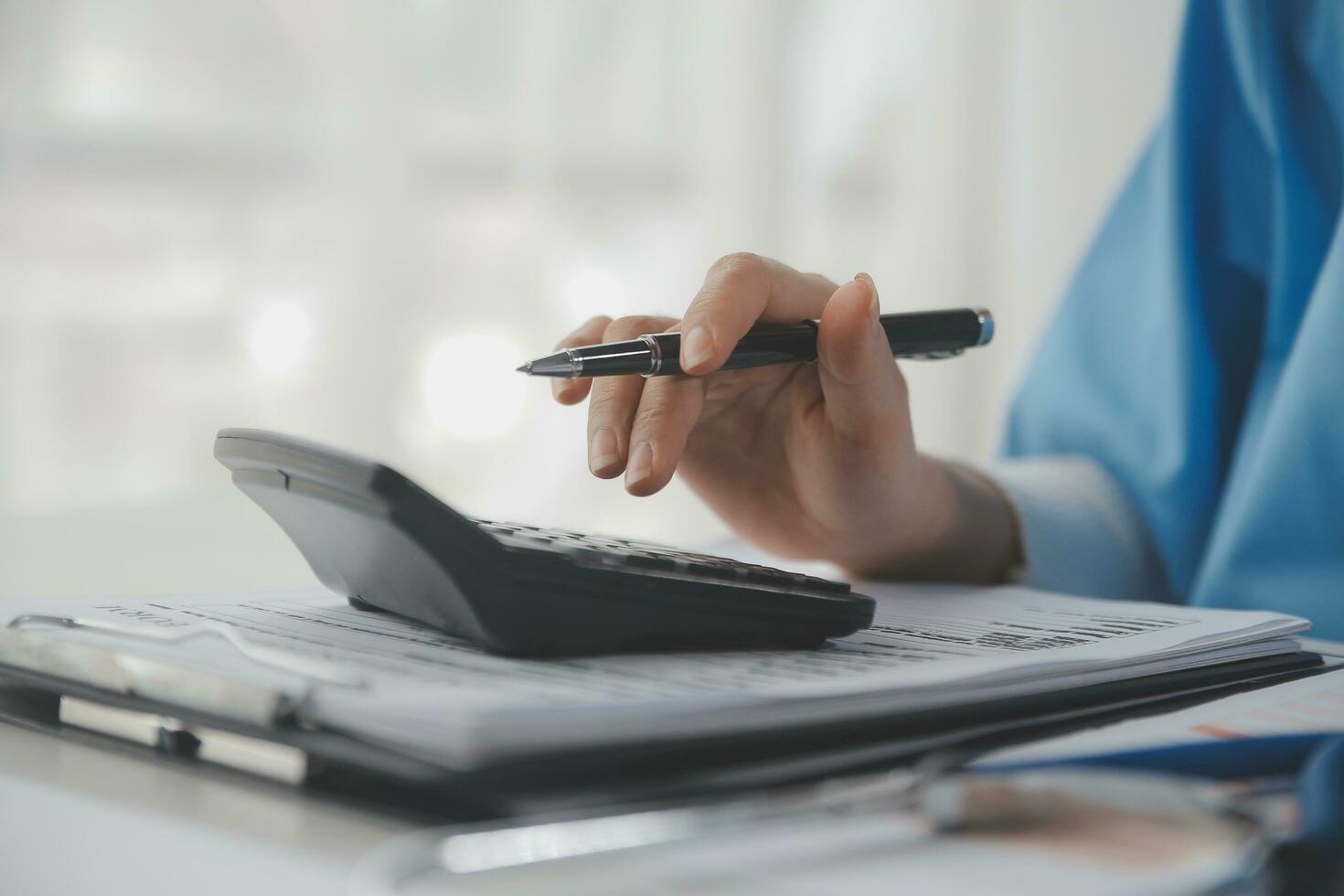 Doctor or physician using calculator and work on laptop computer with medical stethoscope on the desk at clinic or hospital. Medical healthcare costs ,fees and revenue concept. photo