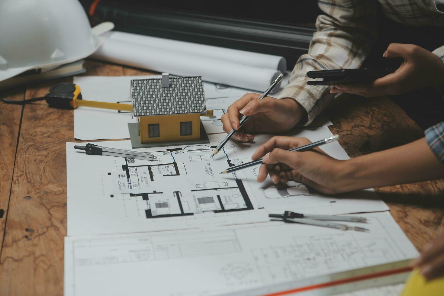 equipo de multiétnico arquitectos trabajando en construcción planes en reunión habitación. ingenieros que se discute en proyecto en oficina. maduro empresario y mujer en pie alrededor mesa trabajando en Plano. foto