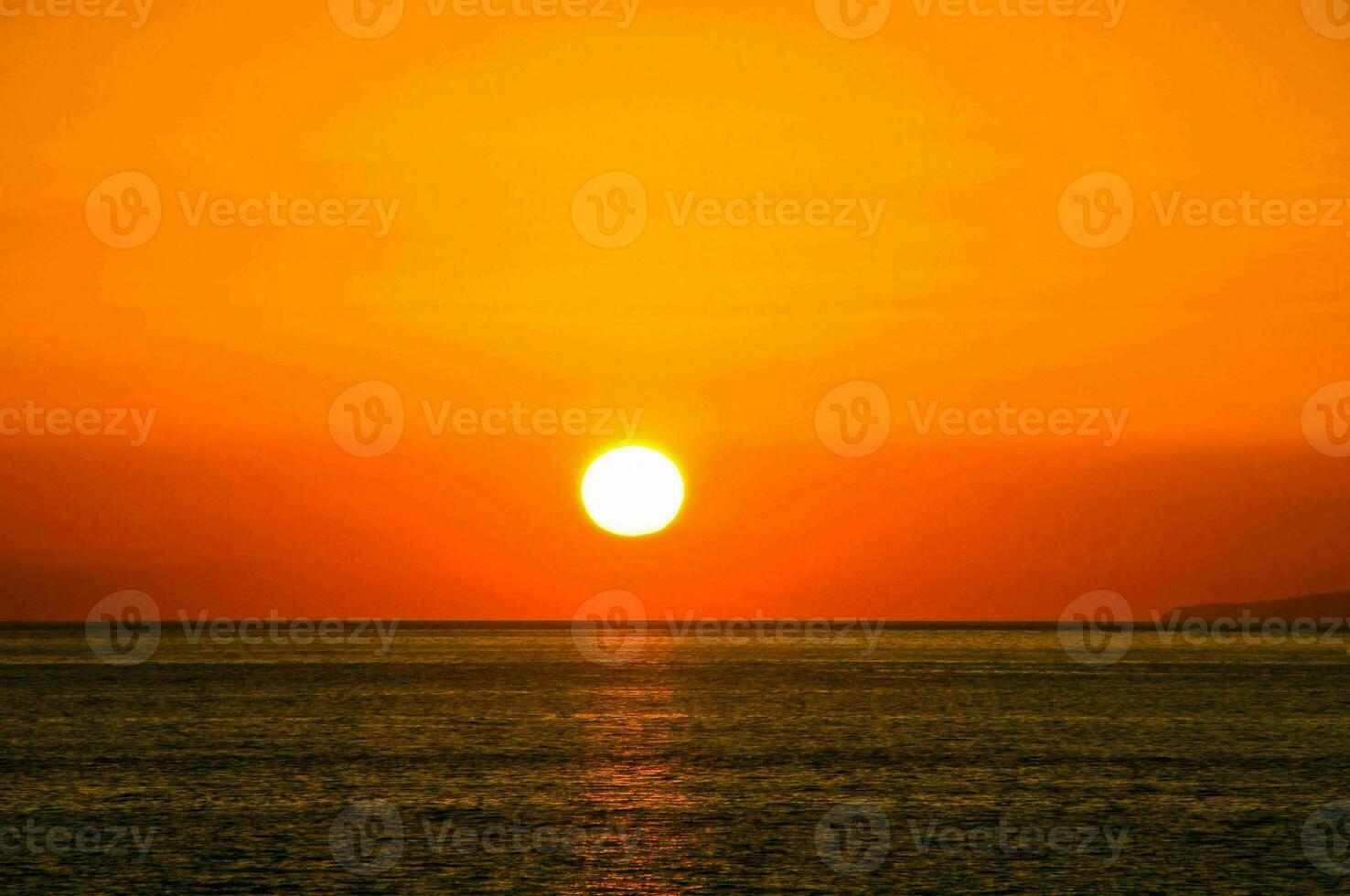 the sun setting over the ocean photo