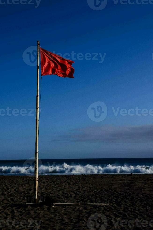 a red flag on the beach near the ocean 32230908 Stock Photo at Vecteezy