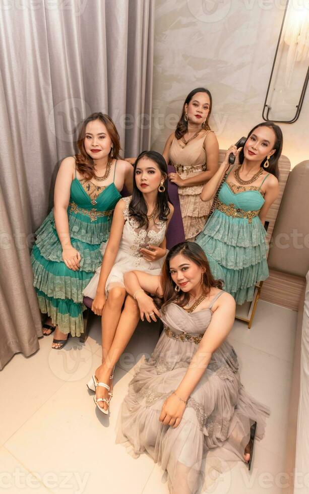 a group of Asian women in luxurious dresses are waiting for dinner in a hotel ballroom photo