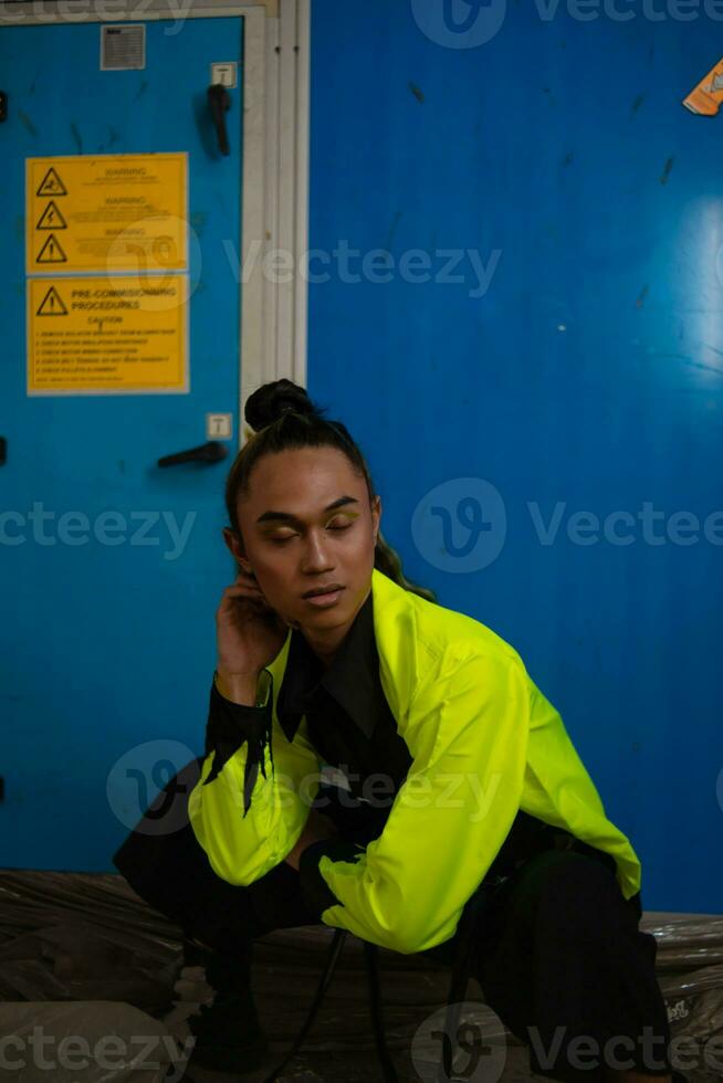 an Asian man with exotic skin squats in front of a blue background photo