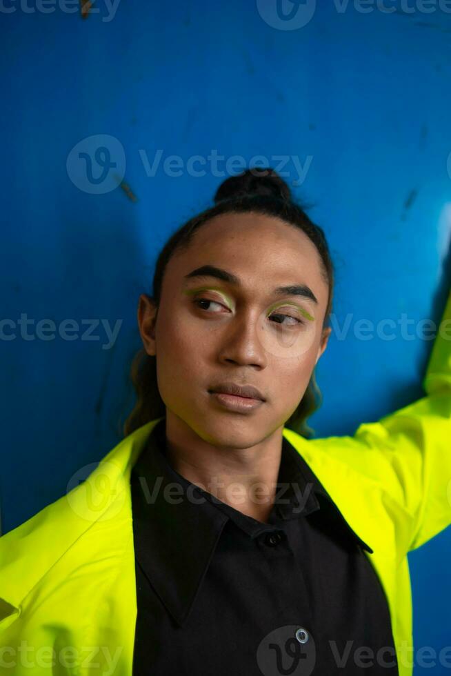 un asiático hombre en un verde chaqueta posando en frente de un azul armario foto