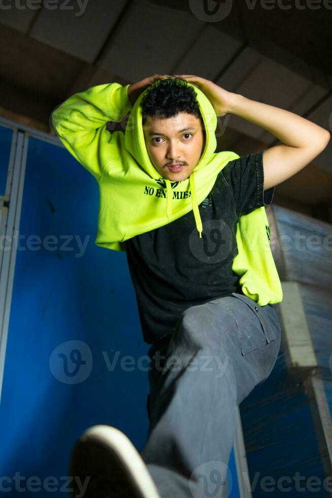 an Asian man with black curly hair posing in a green hoodie photo