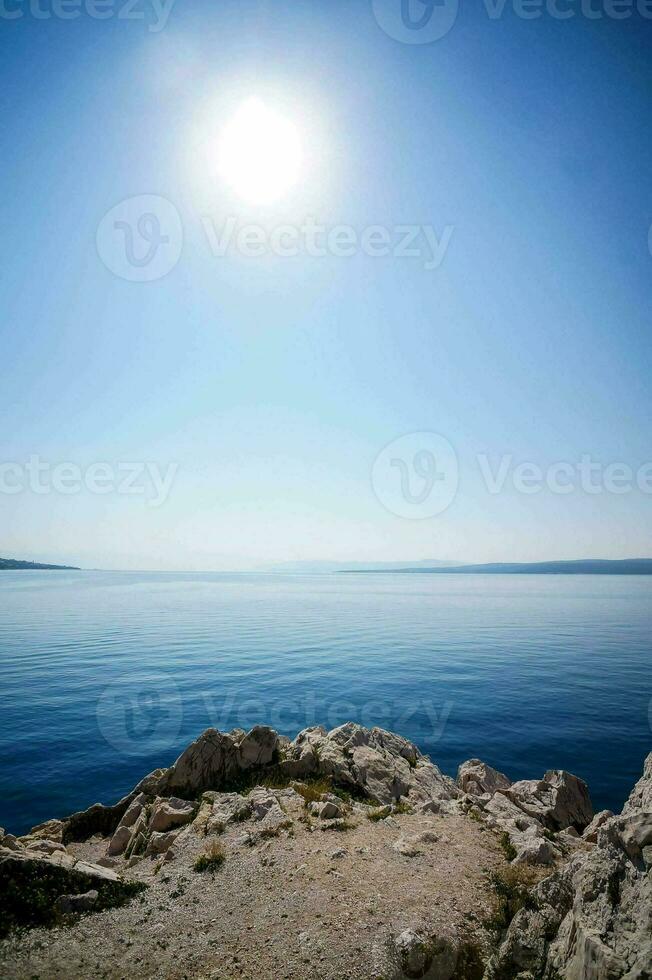 the sun shines over the water in a blue sky photo