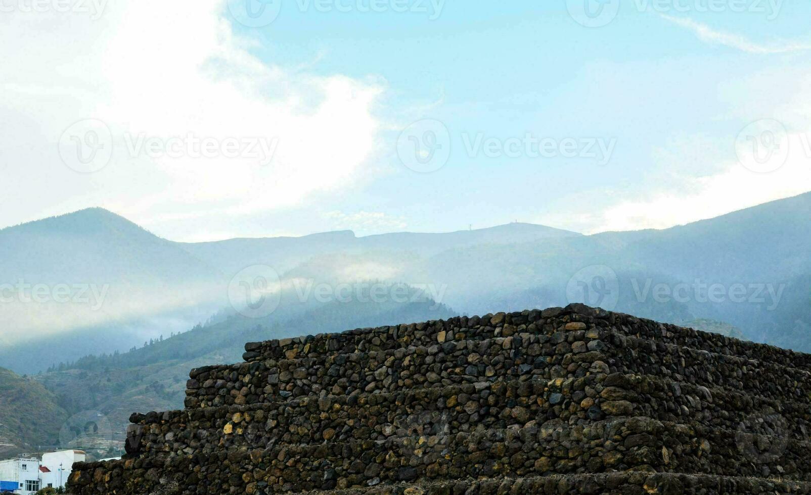 a pyramid of stones in front of mountains photo