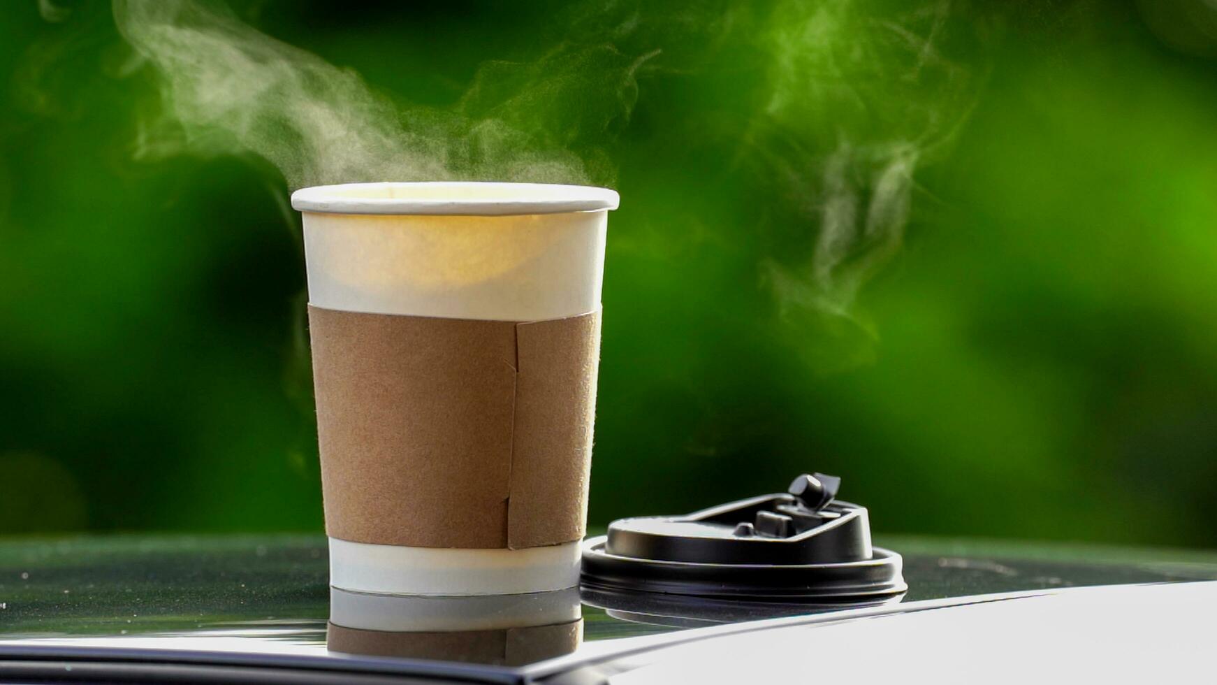 café para llevar en un papel taza en parte superior de el coche techo verde árbol antecedentes a amanecer en el mañana, selectivo enfocar, suave enfocar. foto