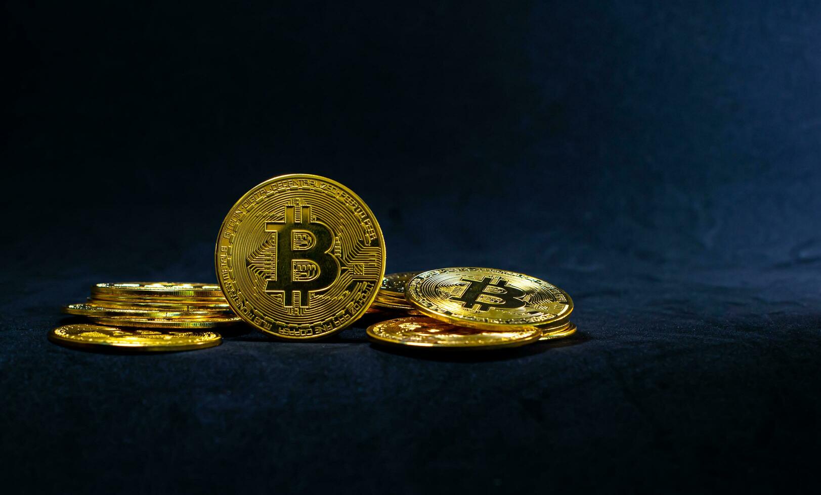 Golden bitcoin in the middle of pile, Bitcoin on dark blue background, Background with ray of light. photo