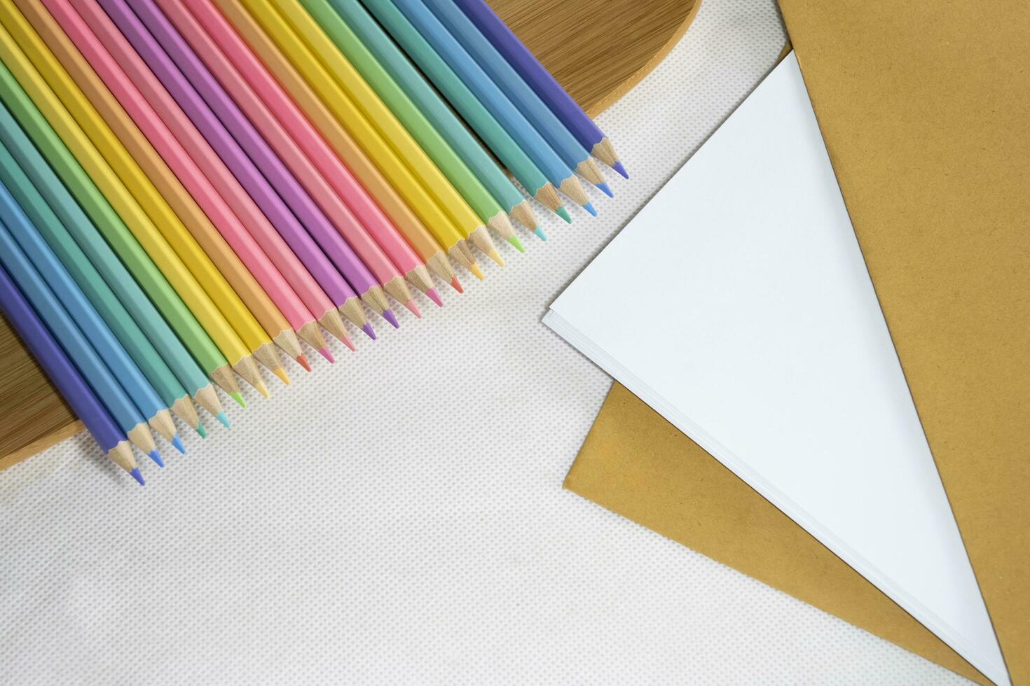 Top left view, Group of color pencil laying in row striaght line on veneer on white and paper background,  copy space. photo