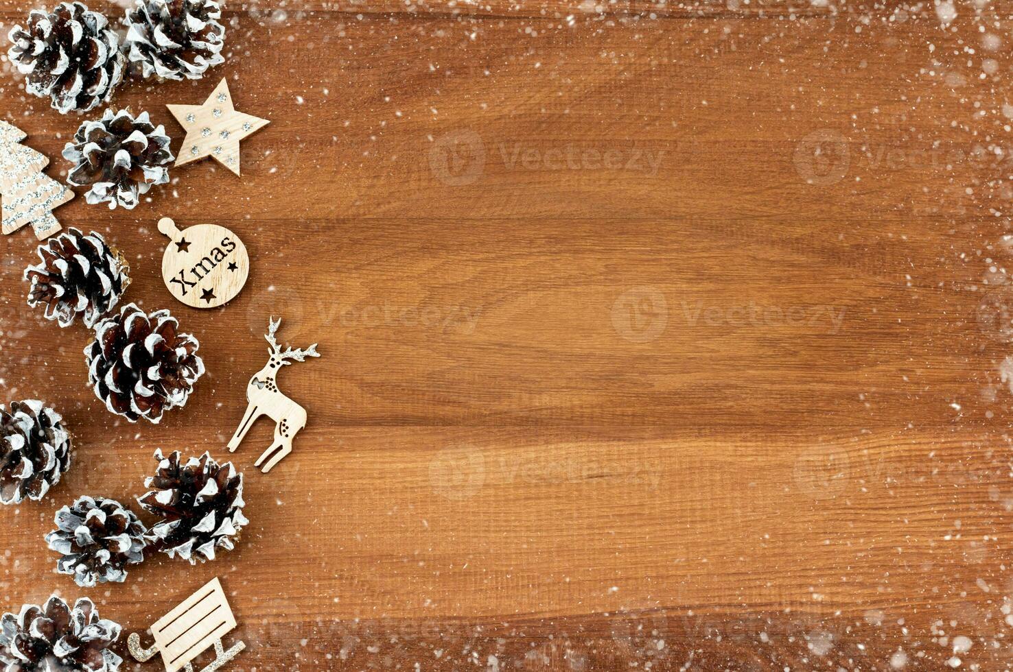 Christmas background. Pine cones and wooden Christmas decorations on a wooden background in a snowy frame photo