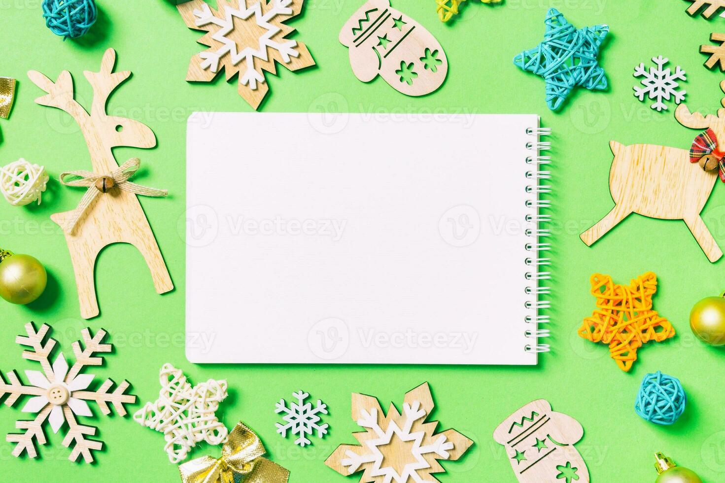 Top view of notebook on green background with New Year toys and decorations. Christmas time concept photo