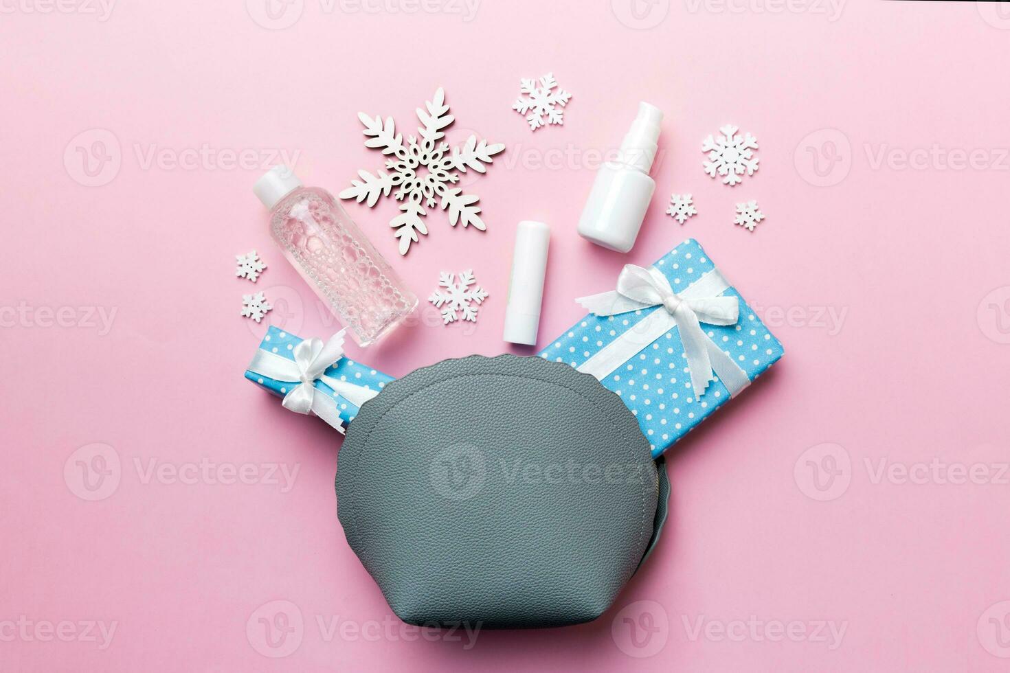 Christmas flat lay with makeup cosmetic products in cosmetic bag on colored background. Top view New year Beauty concept photo