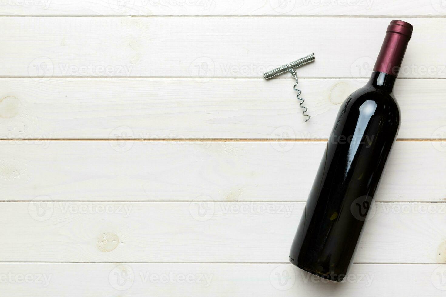One Bottle of red wine with corkscrew on colored table. Flat lay, top view wth copy space photo