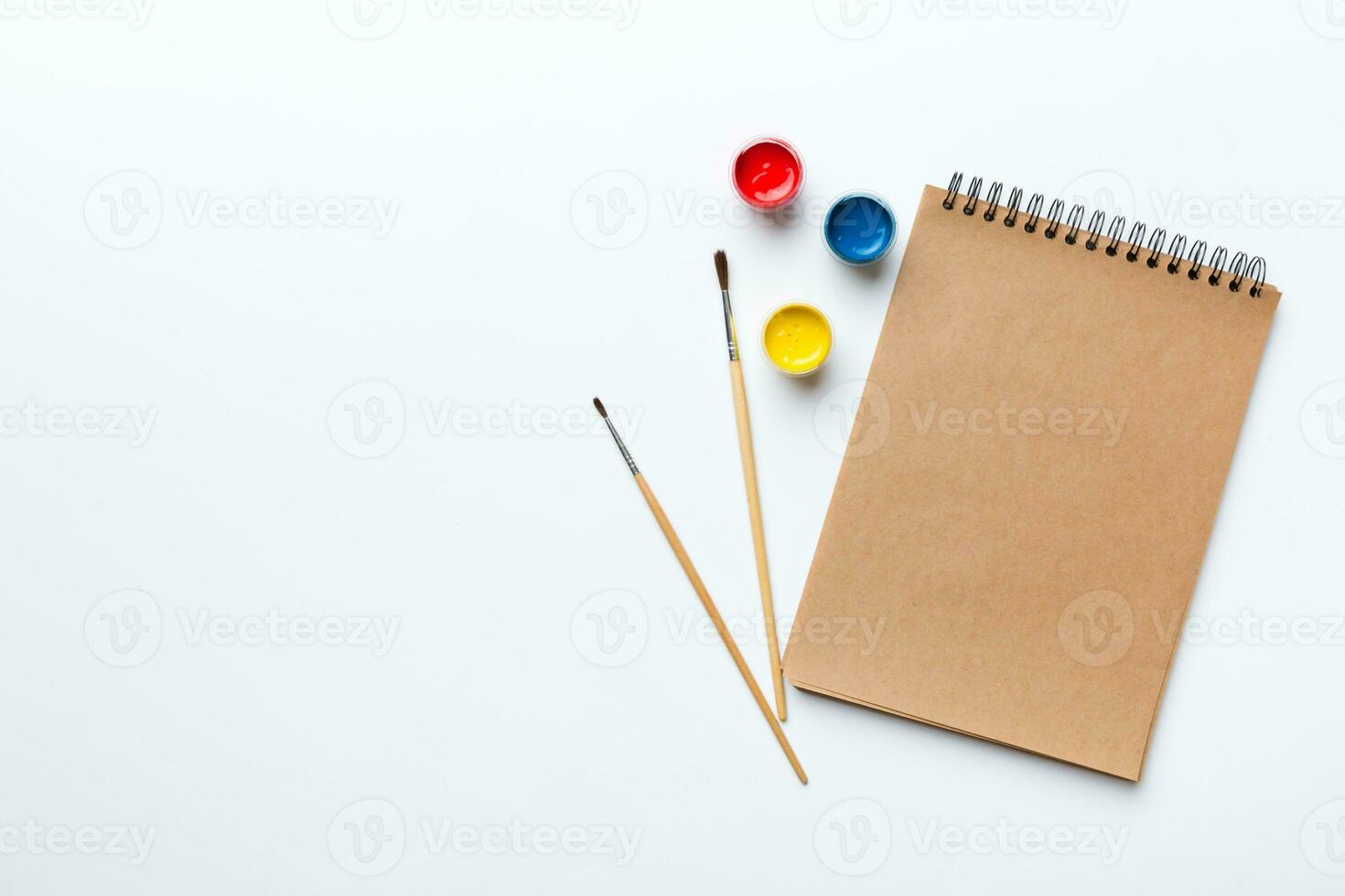 Album pages and paints, pencils, brush on a colored background. Top view with empty space. workplace for creativity. home teaching concept drawing photo