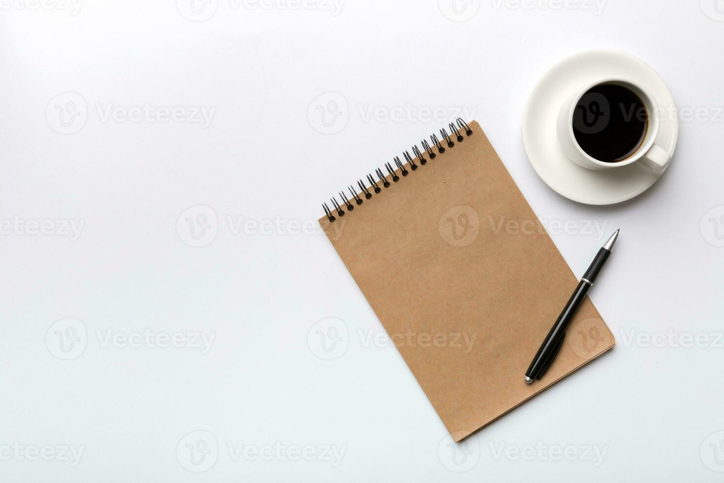 Modern office desk table with notebook and other supplies with cup of coffee. Blank notebook page for you design. Top view, flat lay photo