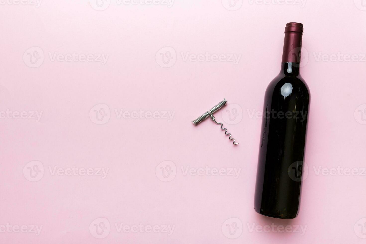 One Bottle of red wine with corkscrew on colored table. Flat lay, top view wth copy space photo