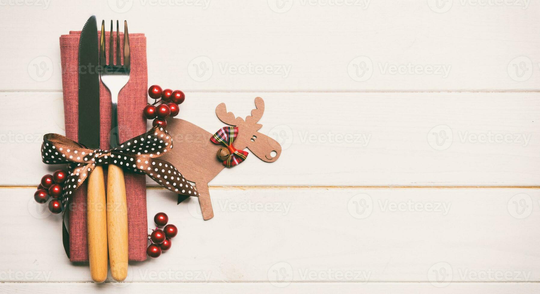 New year set of fork and knife on napkin. Banner Top view of christmas decorations and reindeer on wooden background. Holiday family dinner concept with empty space for your design photo