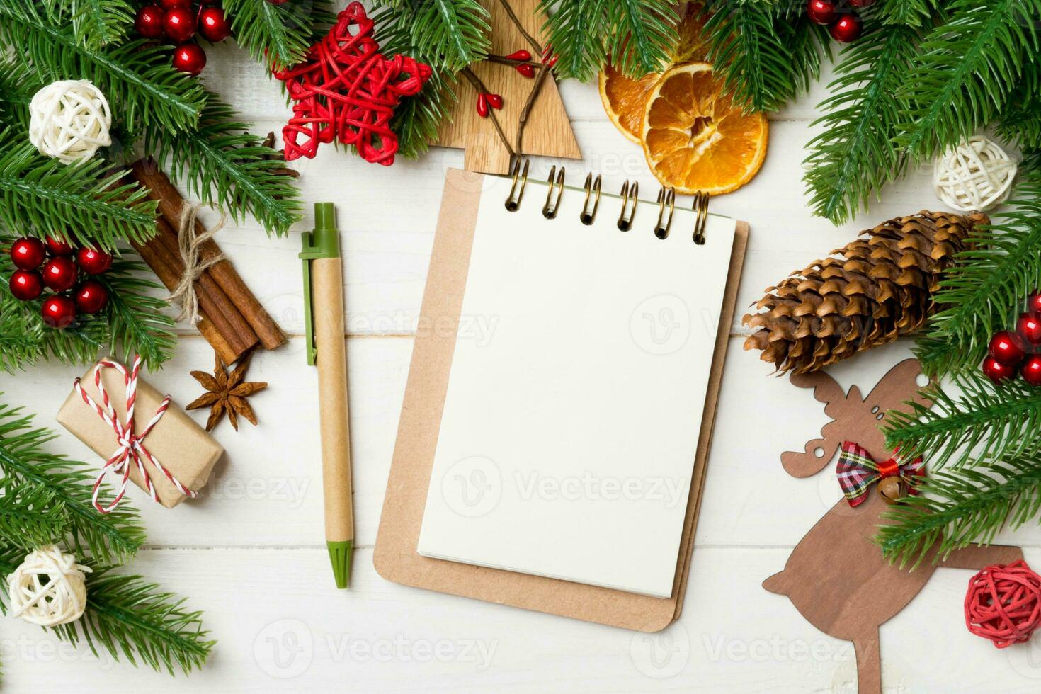 Top view of fir tree branches, notebook and festive decorative toys on wooden background. New Year time concept photo