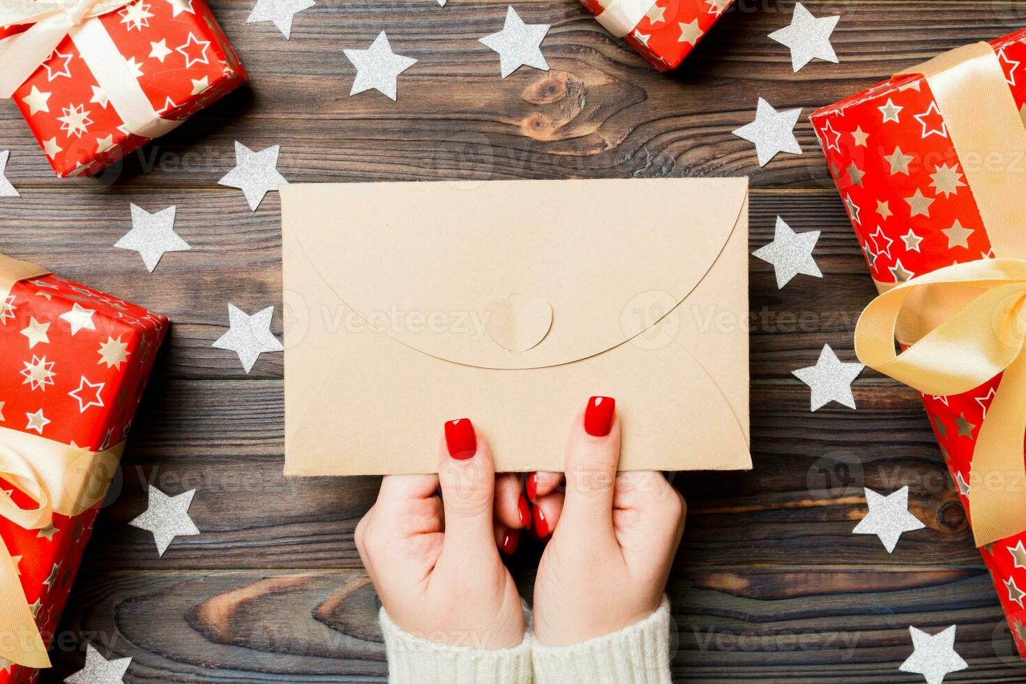 Top view of female hand holding an envelope on wooden background. New Year decorations. Christmas time concept photo