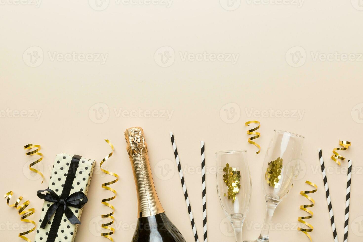 Champagne bottle, glitter and straws on color background. top view