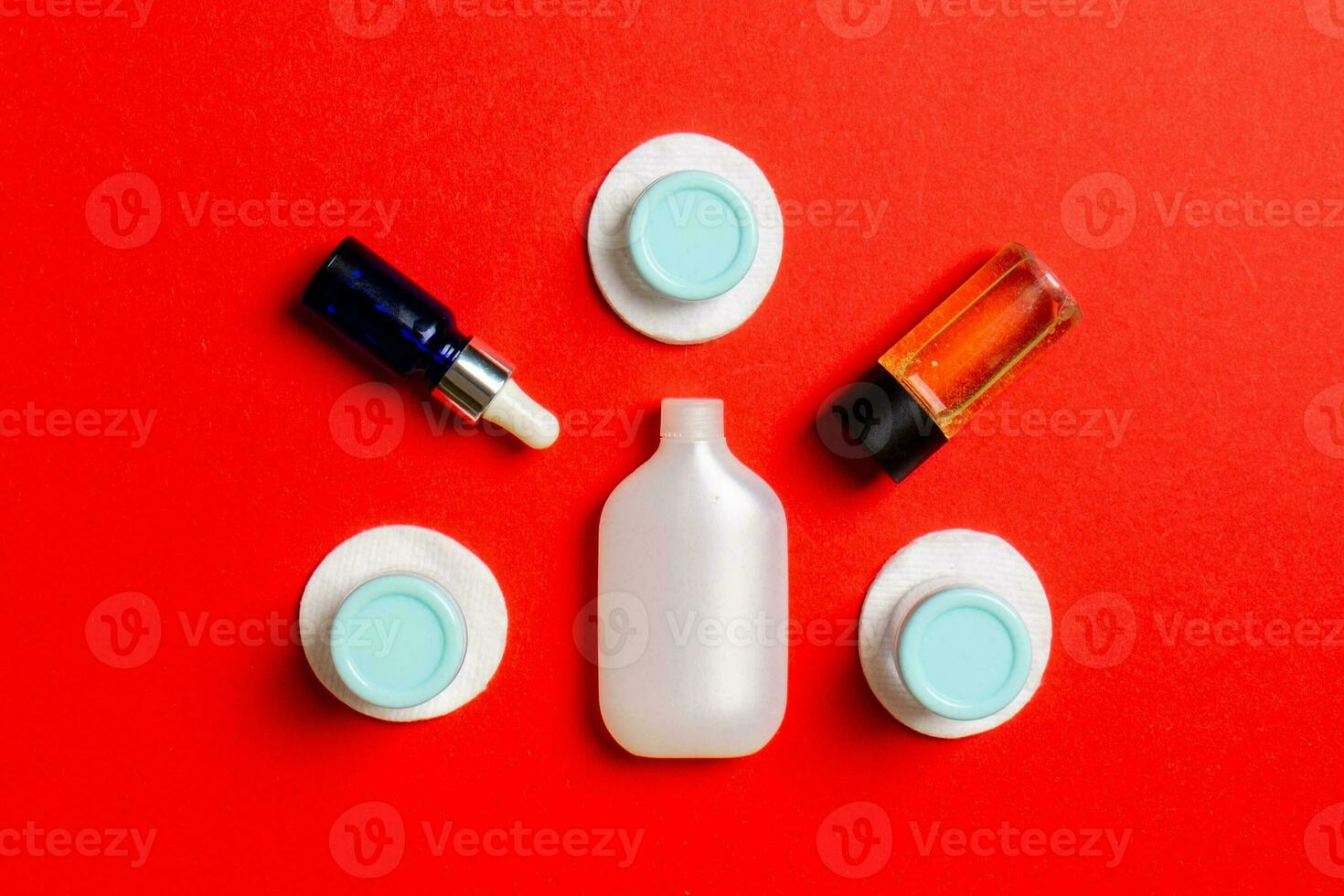 Group of small bottles for travelling on colored background. Copy space for your ideas. Flat lay composition of cosmetic products. Top view of cream containers with cotton pads photo