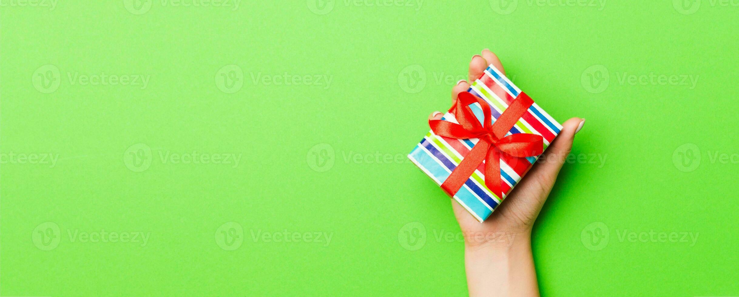 Top view of female hands holding christmas or other holiday handmade present box package in the palms, flat lay table background with copy space photo