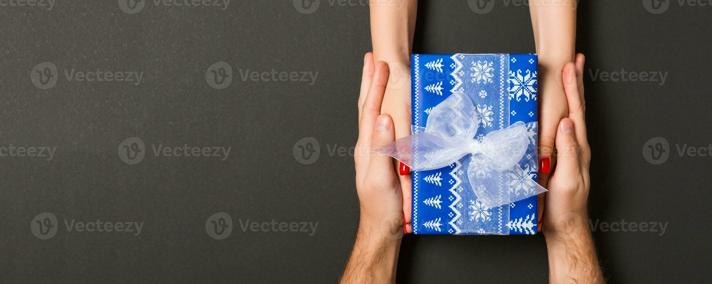Top view of couple giving and receiving a gift on colorful background. Close up of romantic concept photo