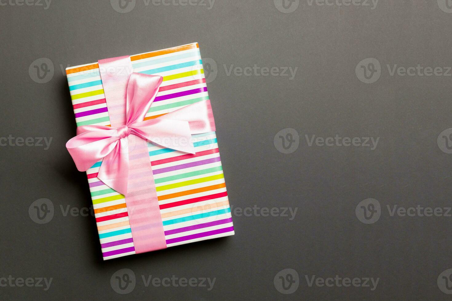 Gift box with pink bow for Christmas or New Year day on black background, top view with copy space photo