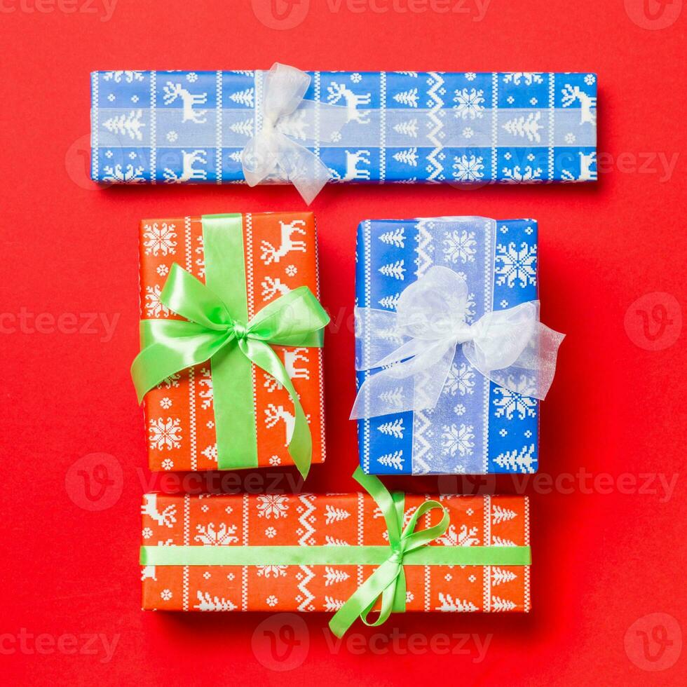 wrapped Christmas or other holiday handmade present in paper with white and green ribbon on red background. Present box, decoration of gift on colored table, top view photo