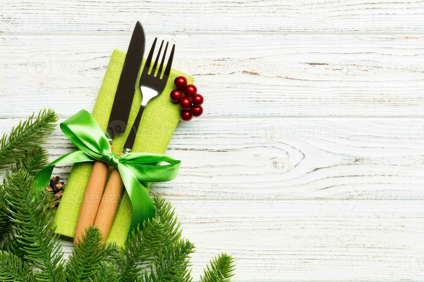 Top view of christmas decorations on wooden background. Fork and knife on napkin tied up with ribbon and empty space for your design. New year pattern concept photo