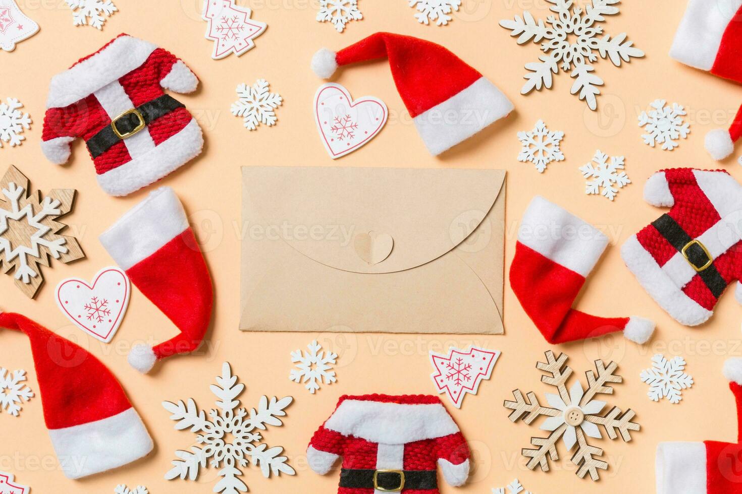 Top view of craft envelope with Christmas decorations and Santa hats on orange background. Happy holiday concept photo