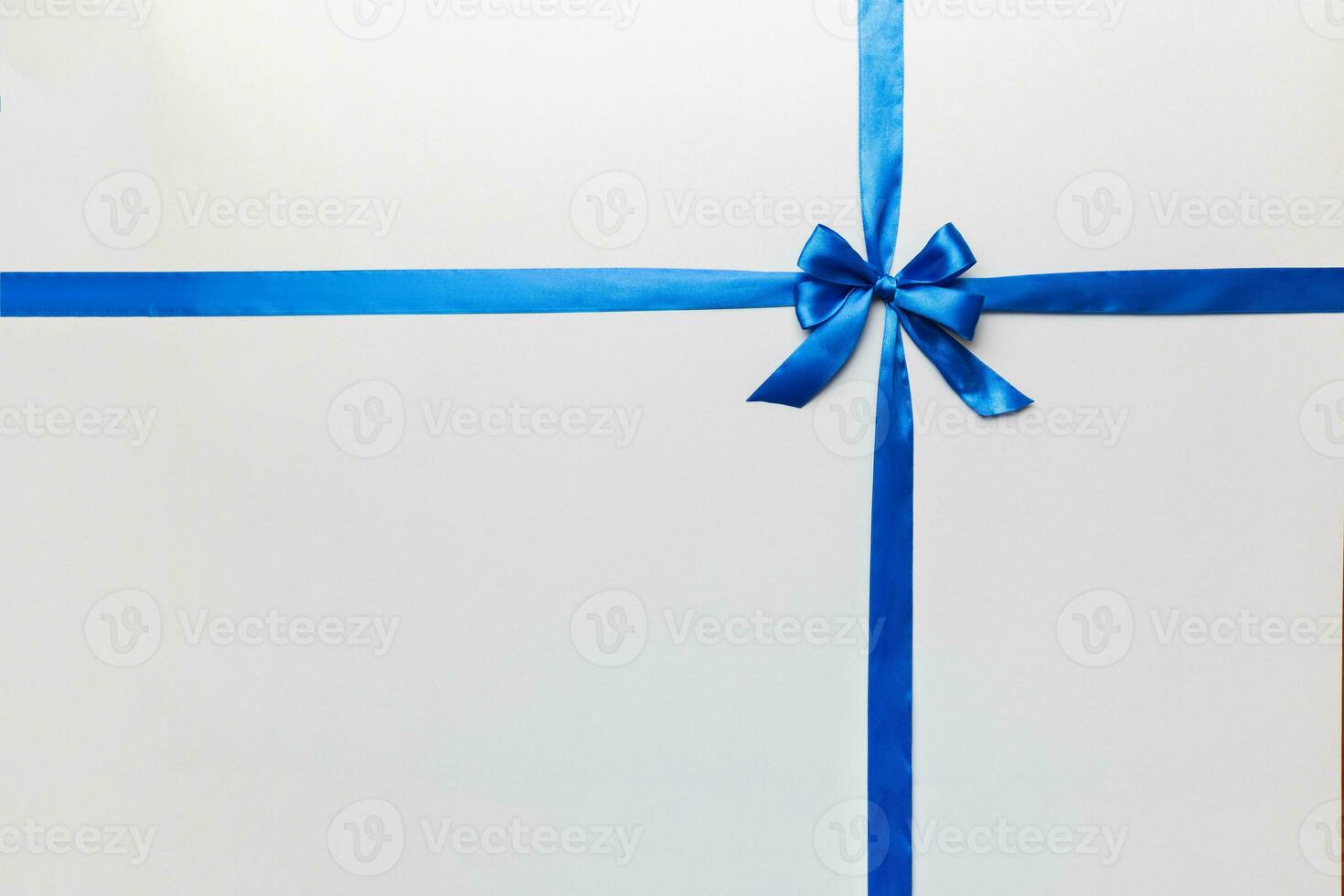 Top view of blue ribbon rolled and blue bow isolated on colored background. Flat lay with copy space photo