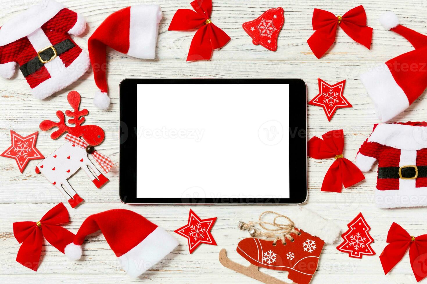 Top view of tablet on holiday wooden background. New Year decorations and toys. Christmas concept photo