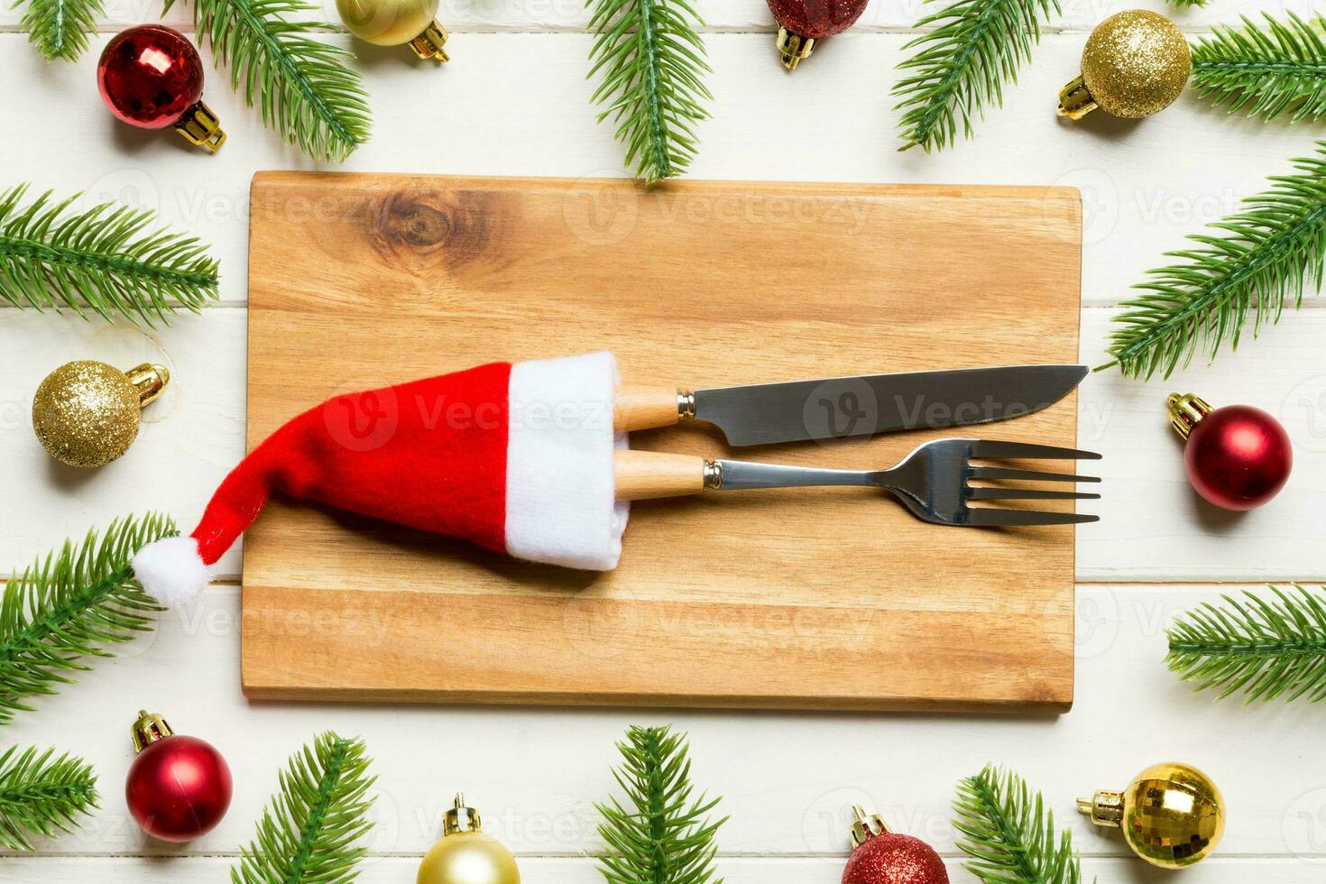Top view of fork, knife and plate surrounded with fir tree and Christmas decoratoins on wooden background. New Year Eve and holiday dinner concept photo