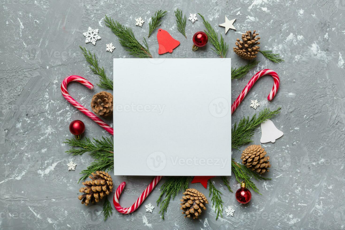 Flat lay Christmas composition. square Paper blank, pine tree branches, christmas decorations on Colored background. Top view, copy space for text photo