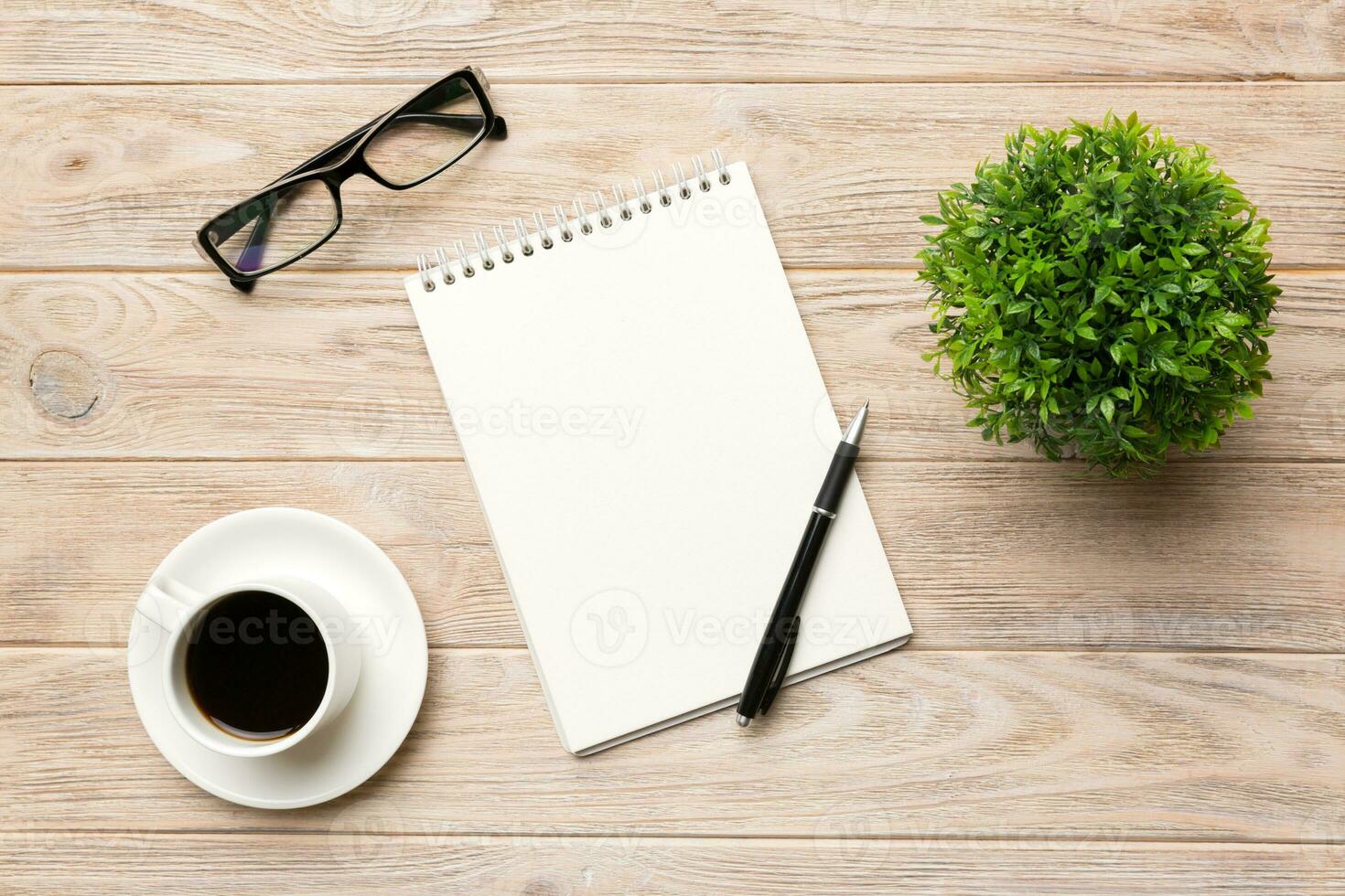 Modern office desk table with notebook and other supplies with cup of coffee. Blank notebook page for you design. Top view, flat lay photo