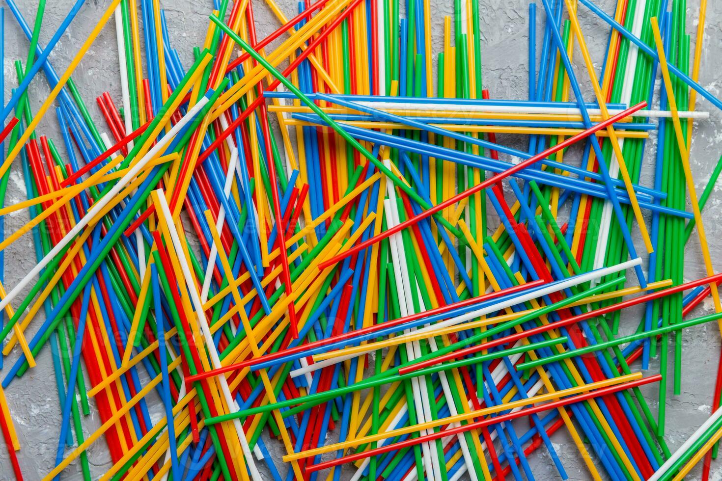 many multi-colored plastic tubes for cocktail on Colored background, top view photo