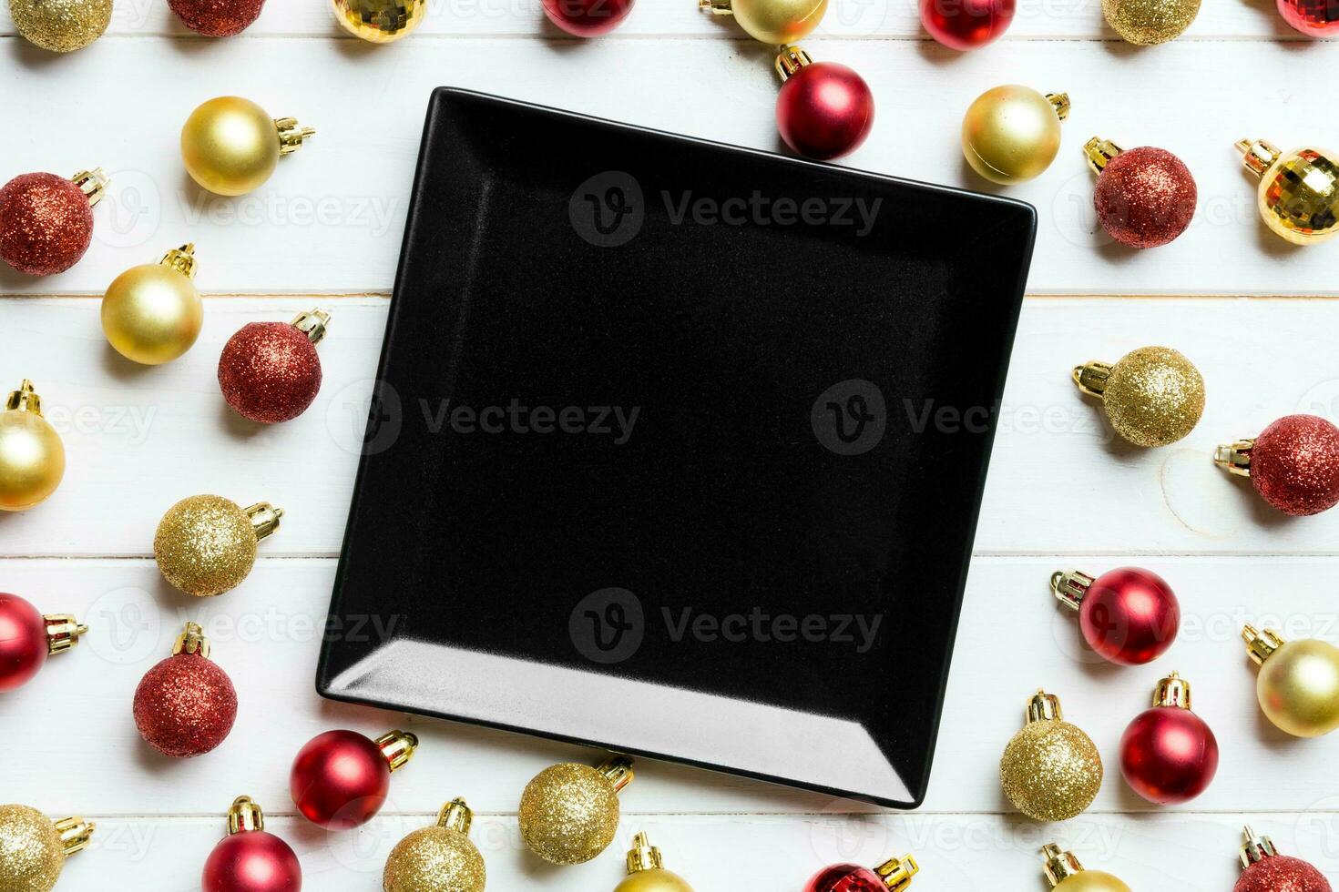 Top view of festive plate with red and golden baubles on wooden background. Christmas decorations and toys. New Year advent concept photo