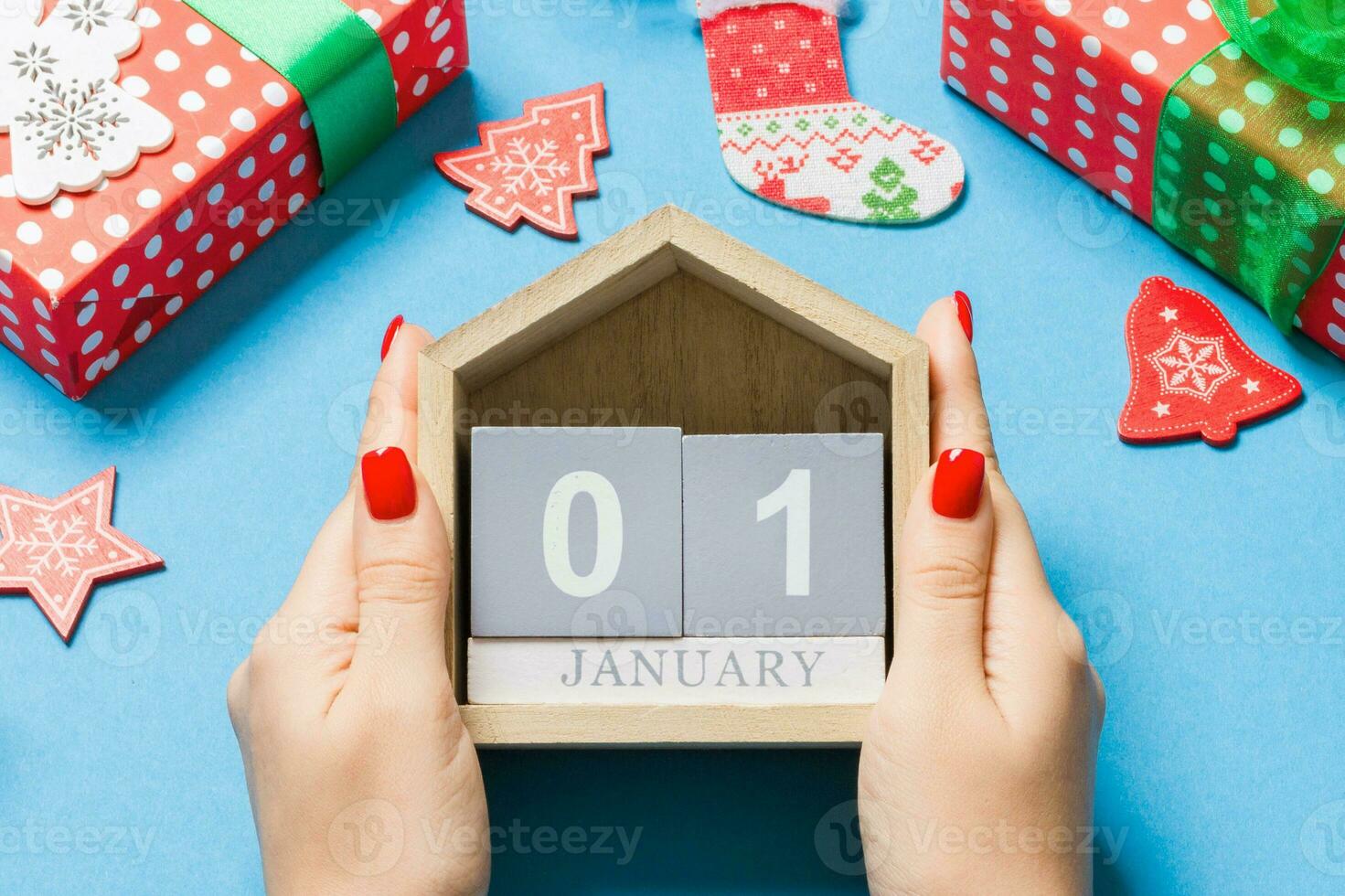 vista superior de las manos femeninas sosteniendo el calendario sobre fondo azul. el primero de enero. decoraciones navideñas. concepto de año nuevo foto