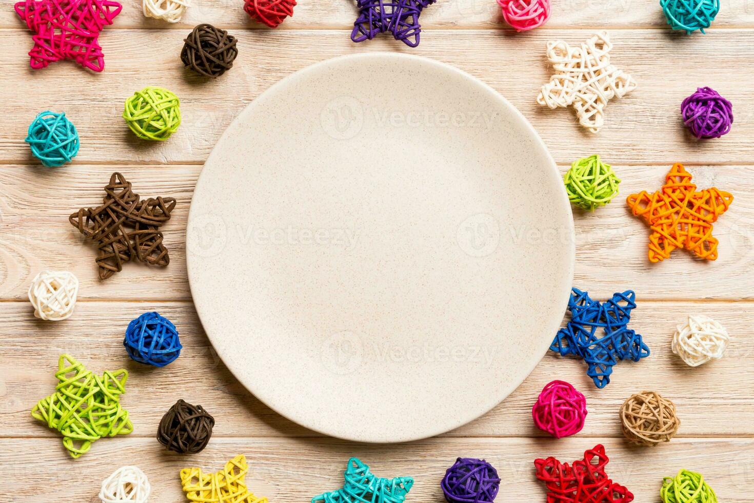 Top view of holiday plate decorated with knitted baubles and stars on wooden background. New Year decorations and toys. Family Christmas dinner concept photo